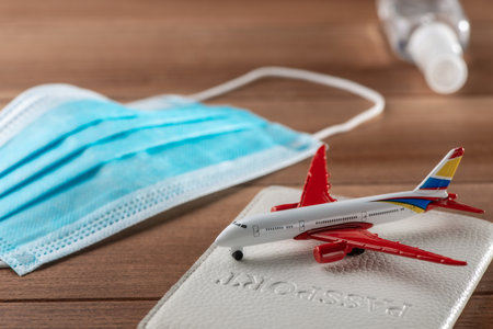 Close-up on airplane toy, passport and surgical face mask on wooden tableの写真素材
