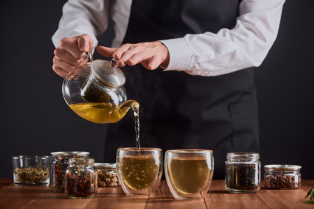 Barista pouring hot green tea into glass cups from a potの写真素材