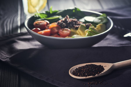 Wooden spoon of quinoa in front of a bowlの写真素材