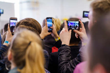 People recording video on their phones during a presentation eventの写真素材