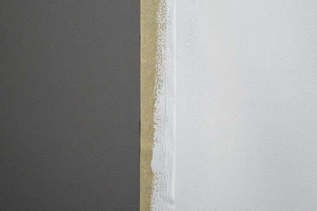 Part of gray wall painted white with masking tapeの写真素材
