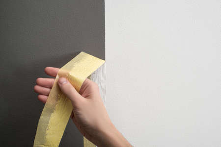 Hand taking off masking tape from the wallの写真素材