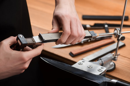 Service man changing a whetstone in a manual sharpener machineの写真素材