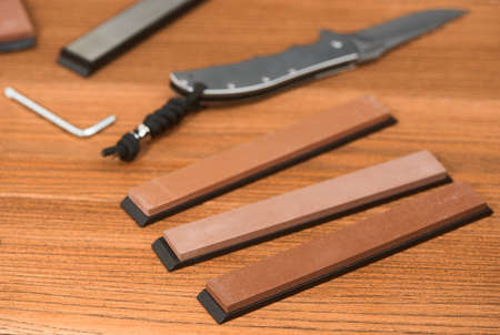 Various whetstones, a folding knife and a hex l-key on wooden backgroundの写真素材