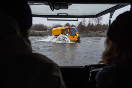 View from a cockpit on a yellow all-terrain vehicle driving through a riverの写真素材