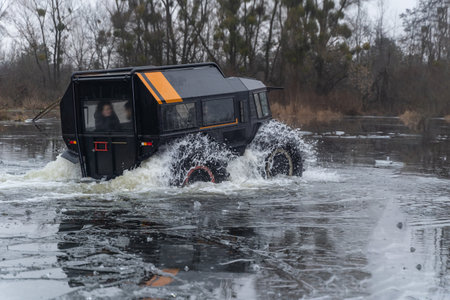 Off-road vehicle with passengers crossing an icy riverの写真素材