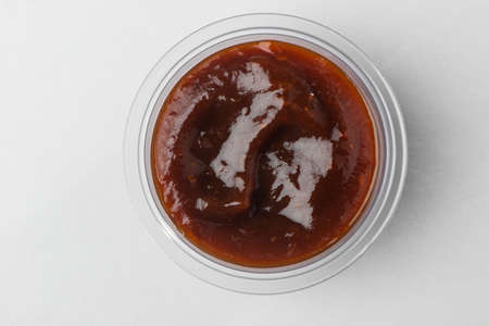 Top view on a cup of barbecue sauce on white background