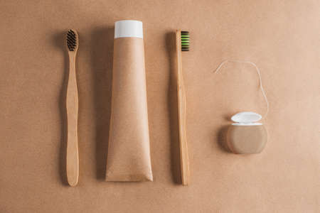 Wooden toothbrushes, organic toothpaste and dental floss on craft paper