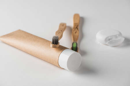 Close-up on a tube of toothpaste, bamboo toothbrushes and dental floss on whiteの写真素材