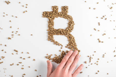Hand destroying bitcoin sign made from pieces of gold on white backgroundの写真素材