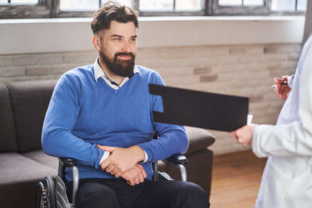 Cheerful man in a wheelchair talking with a physician