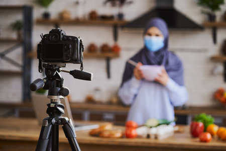 Camera on a tripod in front of a Muslim woman cooking a mealの写真素材