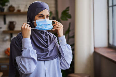 Muslim lady putting a medical mask onto her faceの写真素材