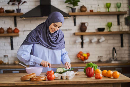 Young Arabian woman cutting a zucchini and smilingの写真素材