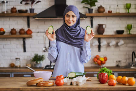 Pretty Muslim woman showing zucchini slices while cooking a mealの写真素材