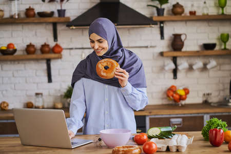 Muslim woman having a video call on her laptop and showing ingredientsの写真素材