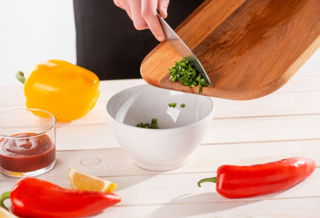 Hand taking cut green pepper off the wooden board with a knifeの写真素材