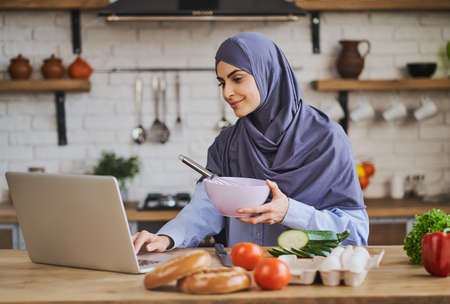 Young muslim woman watching a culinary tutorial and cookingの写真素材