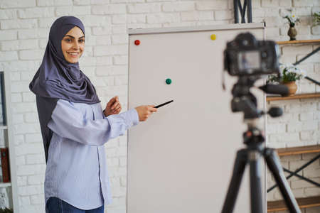 Muslim business lady showing something on a board and looking at the cameraの写真素材