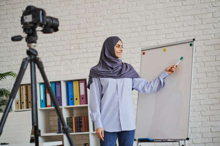 Cheerful Muslim business coach showing something on a whiteboardの写真素材