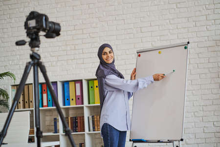 Arabian business woman explaining something and pointing at a whiteboardの写真素材