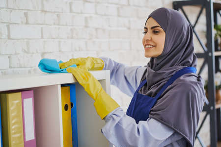 Hardworking Muslim woman cleaning the shelves in the officeの写真素材