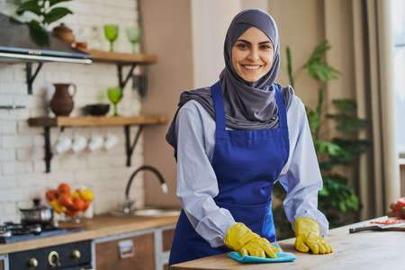 Portrait of an Arabian housewife cleaning a table in the kitchenの写真素材