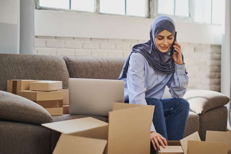 Arabian business woman having a phone call while packaging ordersの写真素材