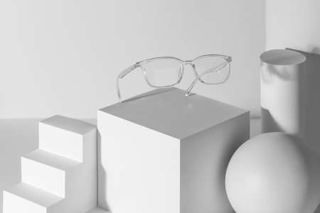 Transparent eyeglasses demonstrated on a set of white 3d shapesの写真素材