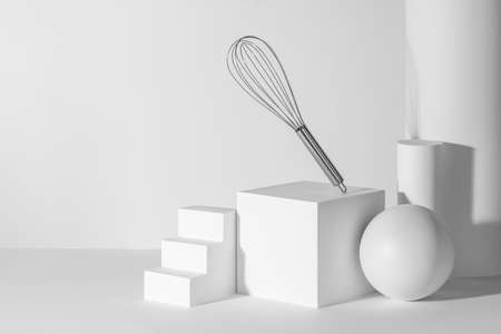 Metal whisk landing on white 3d paper shapes with copy spaceの写真素材