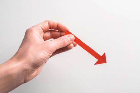 Hand holding a red paper arrow pointing down to the rightの写真素材