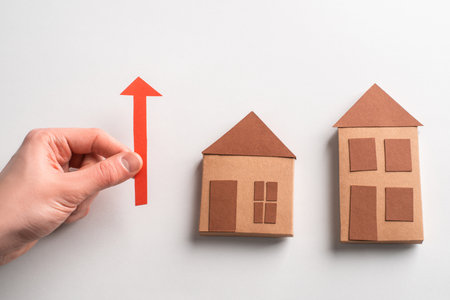 3d paper houses and hand holding a red arrow pointing upの写真素材