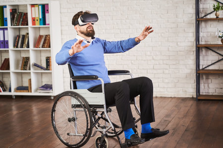 Man sitting in a wheelchair and using a VR headsetの写真素材