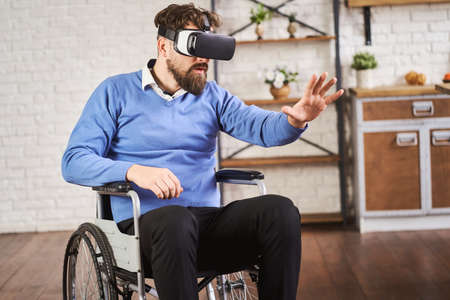 Man sitting in a wheelchair and wearing a VR headsetの写真素材