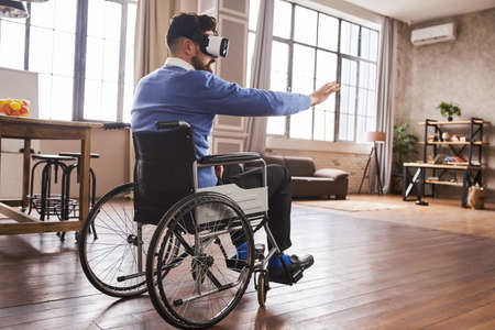 Man with disability sitting in a wheelchair and using a VR headsetの写真素材