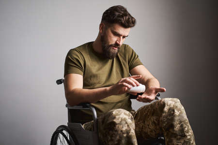 Young disabled man taking prescription pills while sitting in a wheelchairの写真素材