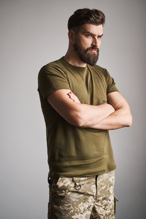 Portrait of a handsome military man holding arms crossed on gray backgroundの写真素材