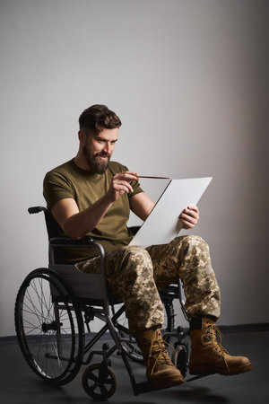 Disabled soldier sitting in a wheelchair and painting on a canvasの写真素材