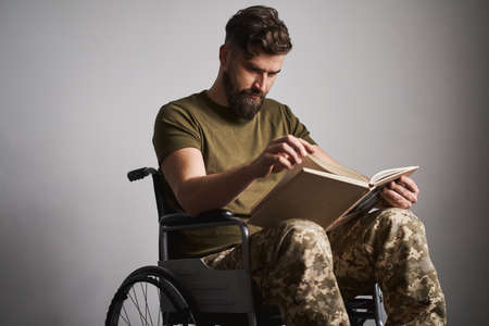 Military man sitting in a wheelchair and watching photos in an albumの写真素材