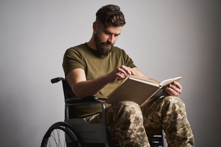 Ex-serviceman sitting in a wheelchair and reading a bookの写真素材