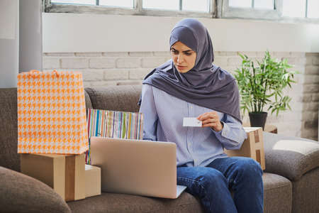 Young Arabian woman trying to buy something in online shop using a credit cardの写真素材