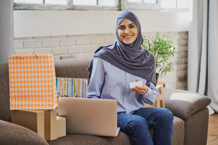Gorgeous Arabian woman holding a credit card and using a laptopの写真素材