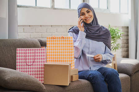 Pretty Arabian woman holding a credit card and talking on the phoneの写真素材
