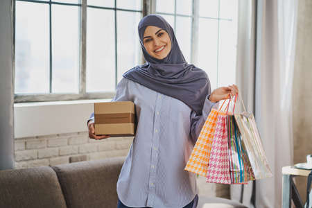 Gorgeous Muslim lady with gift bags, cardboard box and a smile on her faceの写真素材