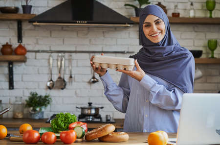 Lovely Muslim lady showing a tray of eggs and giving a smile to the cameraの写真素材