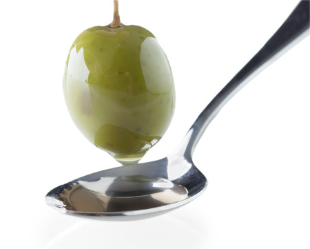 ripe green olive on a spoon on white backgroundの写真素材