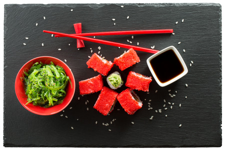 rolls and green seaweed salad on a slate table.の写真素材