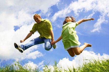 Jump of happiness people on blue sky and green grass background の写真素材