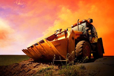 Yellow tractor on golden surise skyの写真素材
