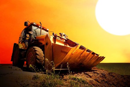 Yellow tractor on golden surise skyの写真素材
